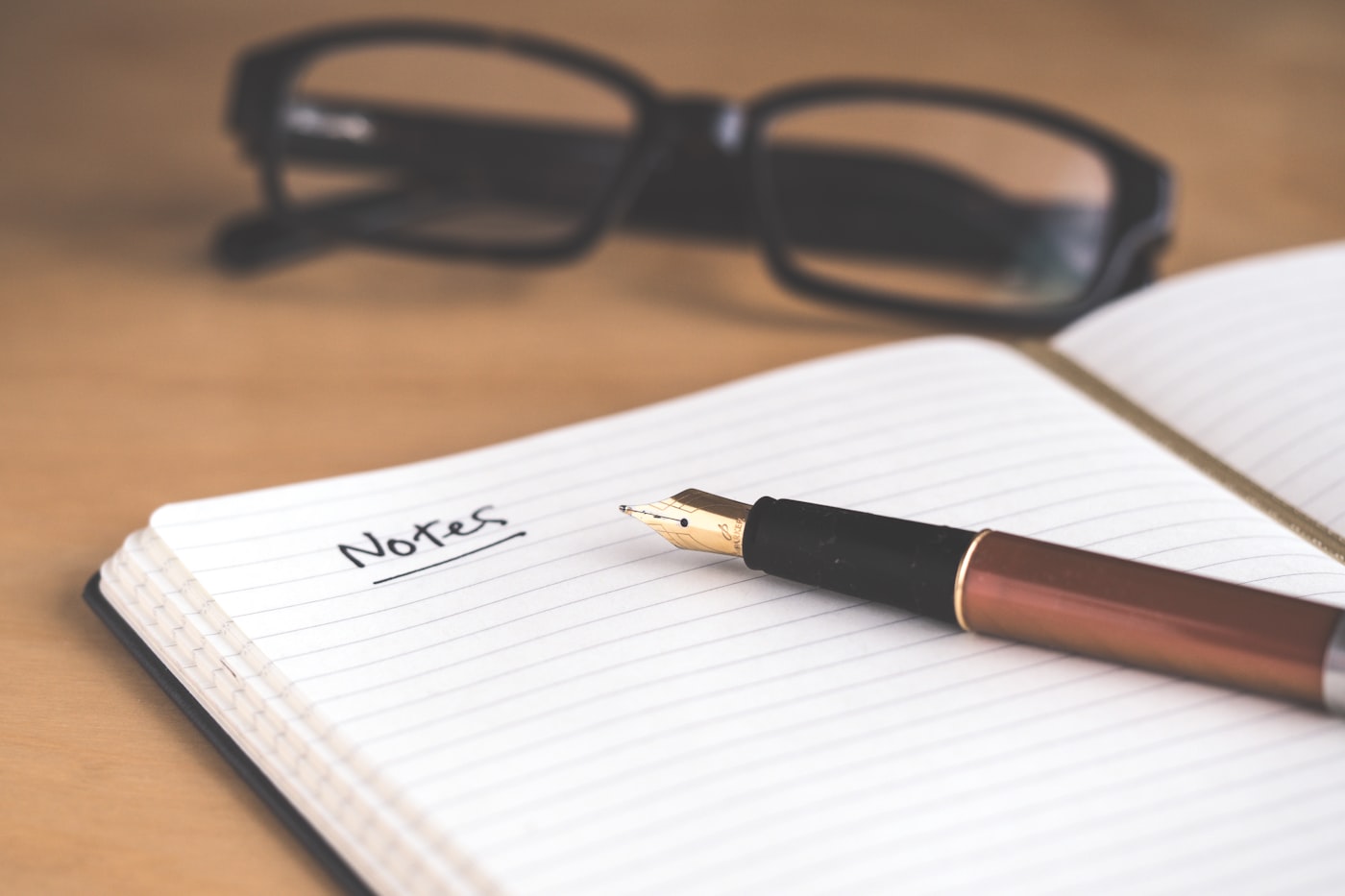 Notizbuch mit Füller und Brille auf einem Schreibtisch